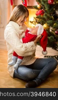 Happy young mother holding baby son in Santa costume