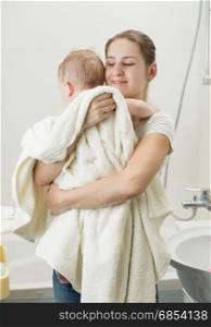 Happy young mother holding her baby after having bath
