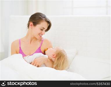 Happy young mother holding sleeping baby