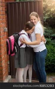 Happy young mother hugging daughters before they leaving for school