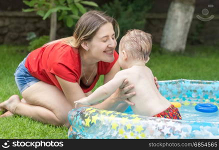 Happy young mother playing with her baby swimming in pool