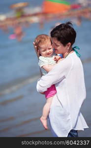 happy young mother walking on beach and push baby carriage