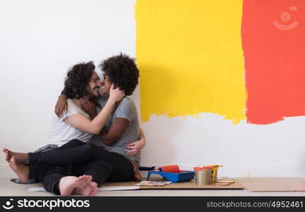 Happy young multiethnic couple relaxing after painting a room in their new house on the floor