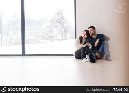happy young multiethnic couple sitting near window at home on cold winter day