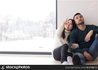 happy young multiethnic couple sitting near window at home on cold winter day