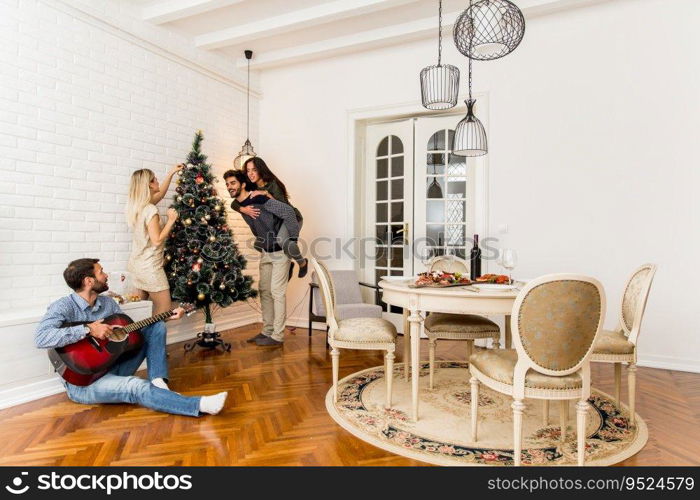 Happy young people decorate fir-tree for holidays of Christmas and New Year at home