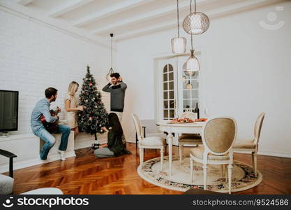 Happy young people decorate fir-tree for holidays of Christmas and New Year at home