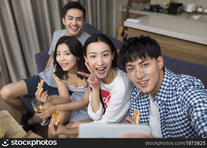 Happy young people gathering in the living room taking selfies
