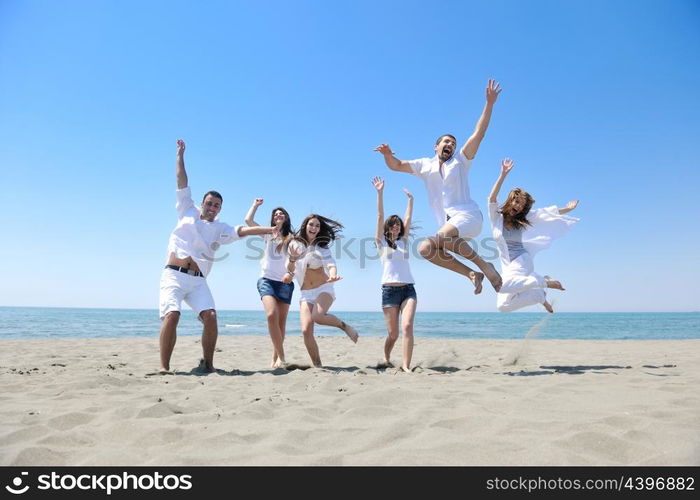 happy young people group have fun run and jump on beach beautiful sand beach