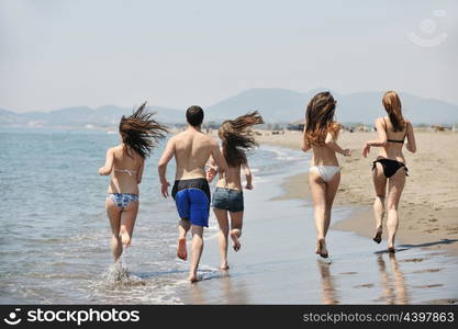 happy young people group have fun run and jump on beach beautiful sand beach