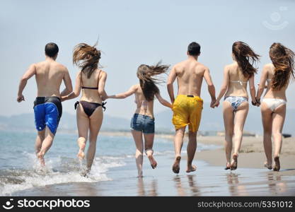 happy young people group have fun run and jump on beach beautiful sand beach