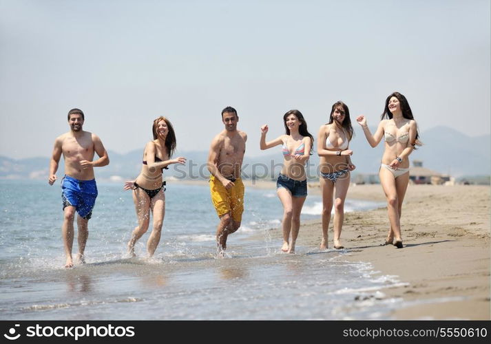 happy young people group have fun run and jump on beach beautiful sand beach