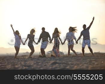 happy young people group have fun run and jump on beach beautiful sand beach