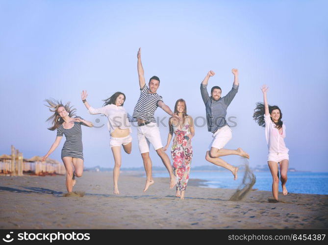 happy young people group have fun run and jump on beach beautiful sand beach