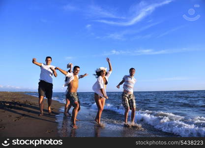 happy young people group have fun white running and jumping on beacz at sunset time