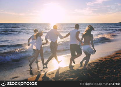 happy young people group have fun white running and jumping on beacz at sunset time