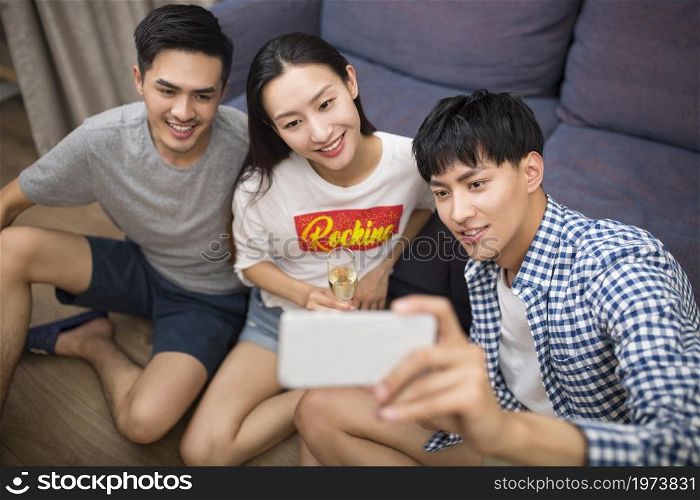 Happy young people taking selfies with a phone in the living room