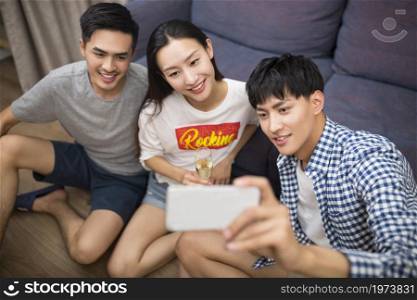 Happy young people taking selfies with a phone in the living room