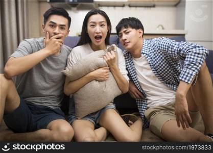 Happy young people watching TV at home