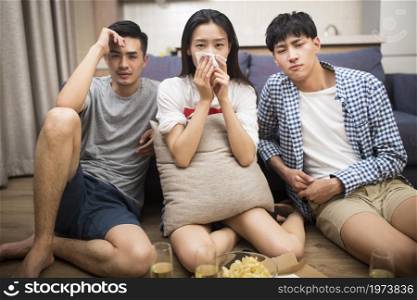 Happy young people watching TV at home