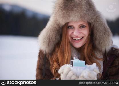 happy young redhair girl with gift and snow in hands. Christmas and winter shopping.