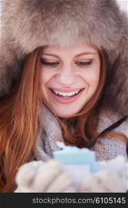 happy young redhair girl with gift and snow in hands. Christmas and winter shopping.
