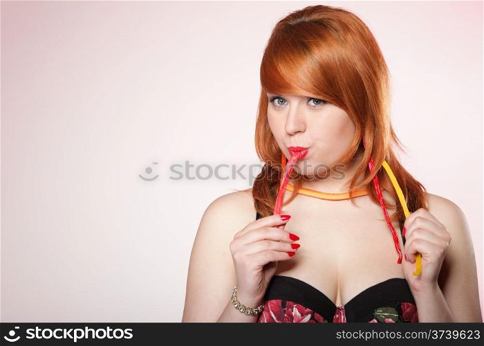happy young redhair woman with gummy candy pink background
