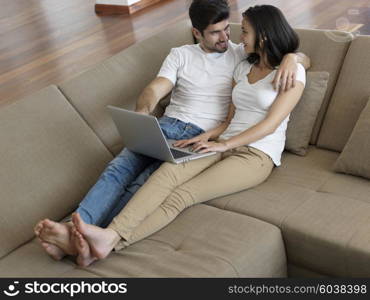 happy young relaxed couple working on laptop computer at modern home indoor