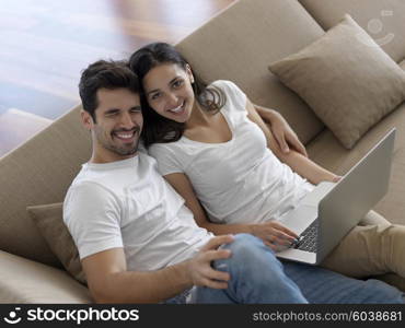 happy young relaxed couple working on laptop computer at modern home indoor