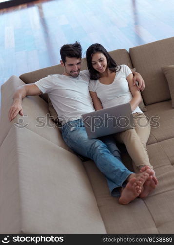 happy young relaxed couple working on laptop computer at modern home indoor