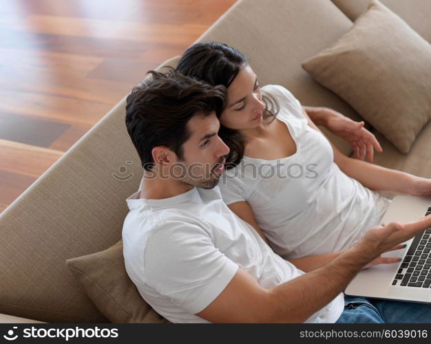 happy young relaxed couple working on laptop computer at modern home indoor