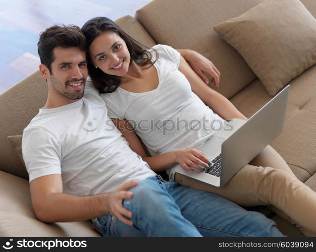 happy young relaxed couple working on laptop computer at modern home indoor