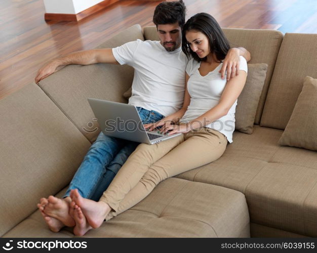 happy young relaxed couple working on laptop computer at modern home indoor