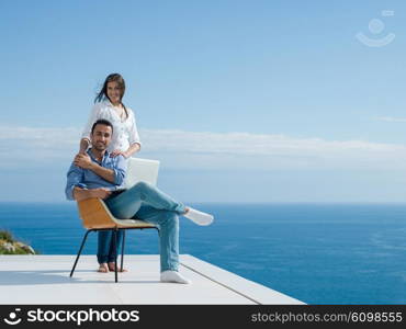 happy young relaxed couple working on laptop computer at modern home indoor