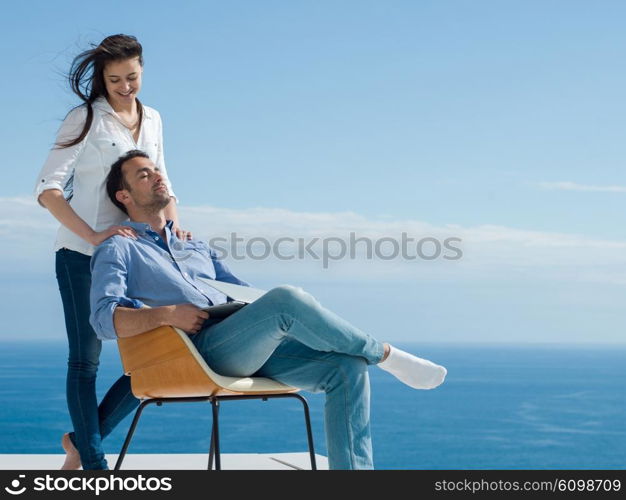 happy young relaxed couple working on laptop computer at modern home indoor