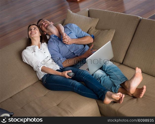 happy young relaxed couple working on laptop computer at modern home indoor