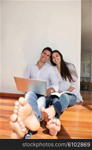 happy young relaxed couple working on laptop computer at modern home indoor