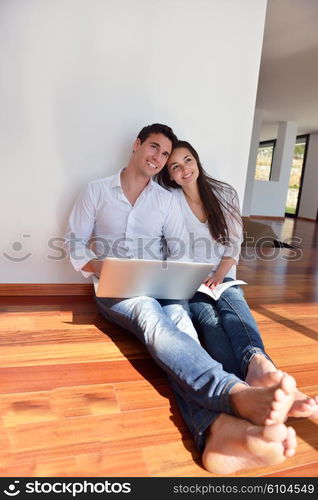 happy young relaxed couple working on laptop computer at modern home indoor