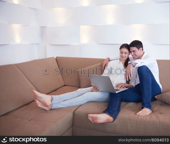 happy young relaxed couple working on laptop computer at modern home interior