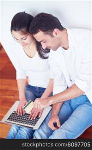 happy young relaxed couple working on laptop computer at modern home interior