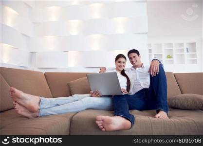 happy young relaxed couple working on laptop computer at modern home interior