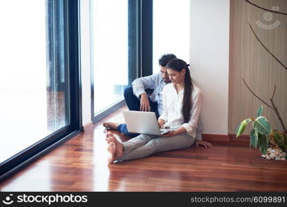 happy young relaxed couple working on laptop computer at modern home interior