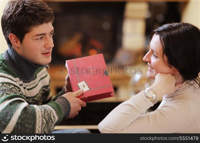 happy Young romantic couple relax on sofa in front of fireplace at winter season in home