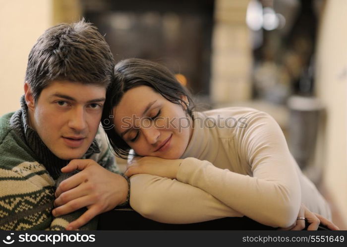 happy Young romantic couple sitting on sofa in front of fireplace at winter season in home