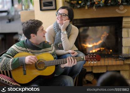 happy Young romantic couple sitting on sofa in front of fireplace at winter season in home