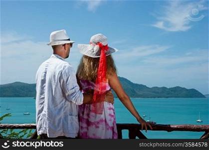 happy young romantic couple together looking out to tropical sea