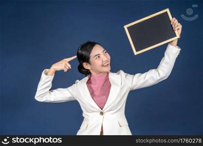 Happy young smiling Asian woman holding copy space empty message blackboard on blue color background, thinking and specking via balloon blank paper, Private opinion for advertisement Concept