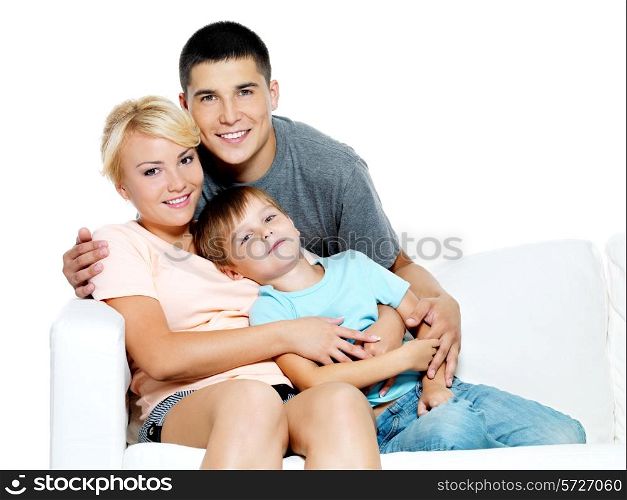 Happy young smiling family with kid sitting on white sofa - Isolated