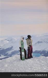happy young snowboarder couple relax at top of mountain at beautiful sunny winter day