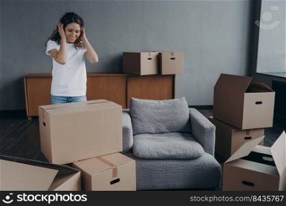 Happy young spanish woman relocates alone. Single lady moves and packing things. Girl packing cardboard boxes. European woman unpacking boxes in new house. Real estate purchase and mortgage concept.. Happy young spanish woman relocates alone. Girl is packing cardboard boxes. Mortgage concept.